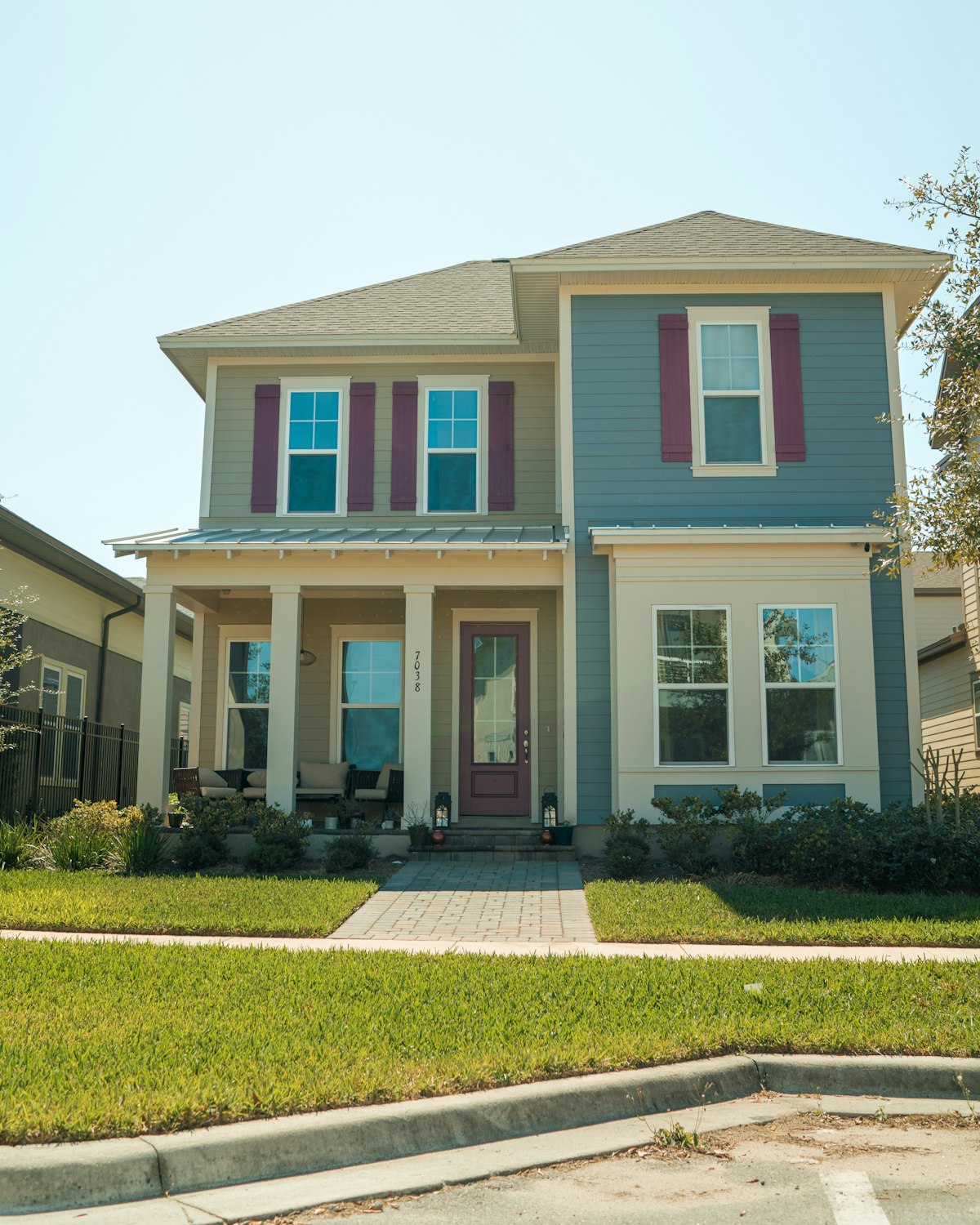 Two-story home freshly painted in blue with maroon shutter accents