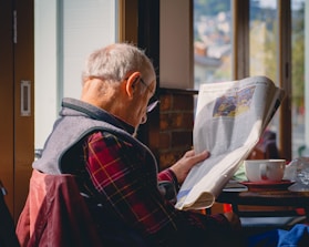 a man sitting at a table reading a newspaper