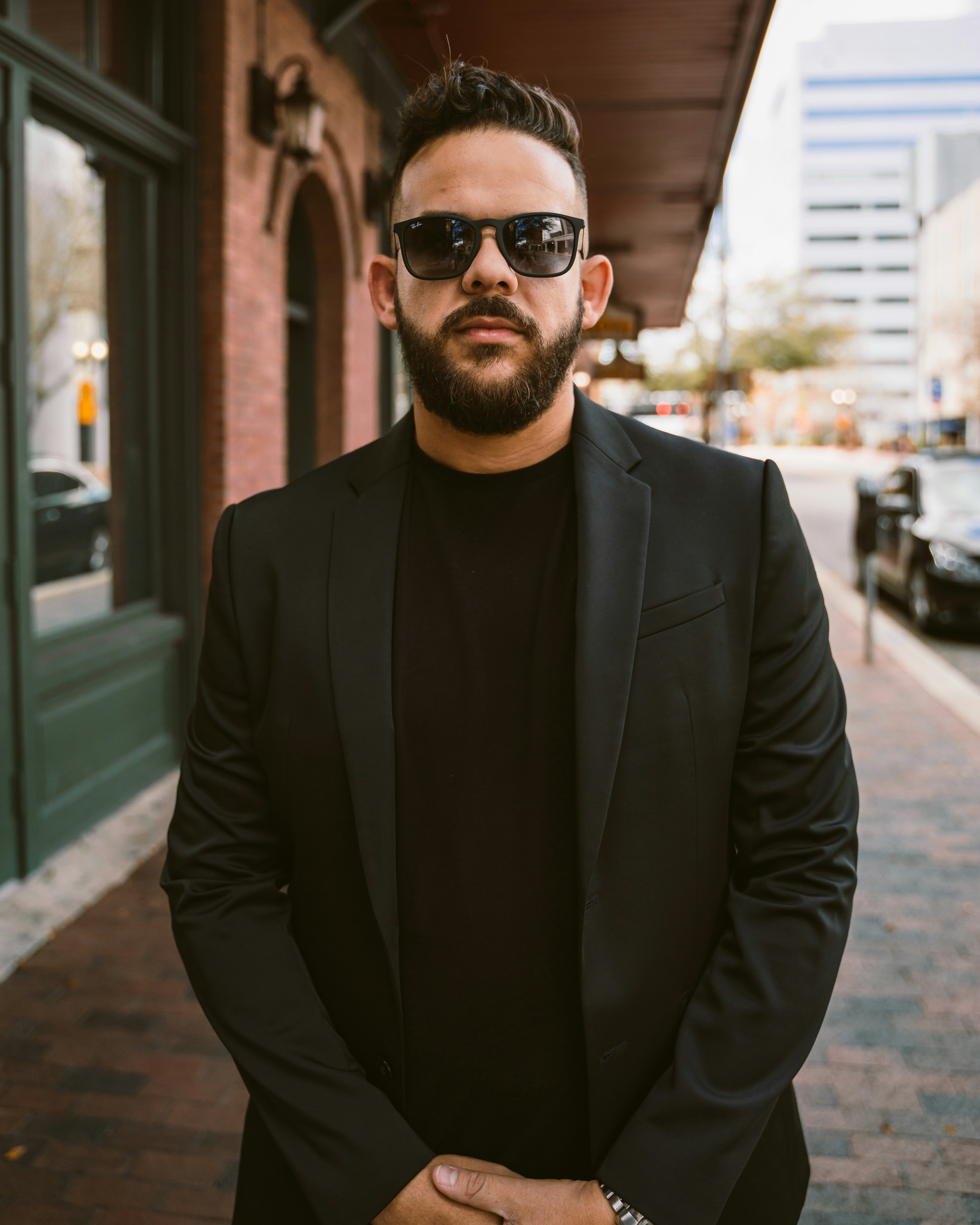 a man in a suit and sunglasses standing on a sidewalk
