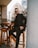 a man in a suit and sunglasses sitting on a stool