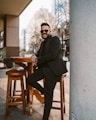 a man in a suit and sunglasses sitting at a table