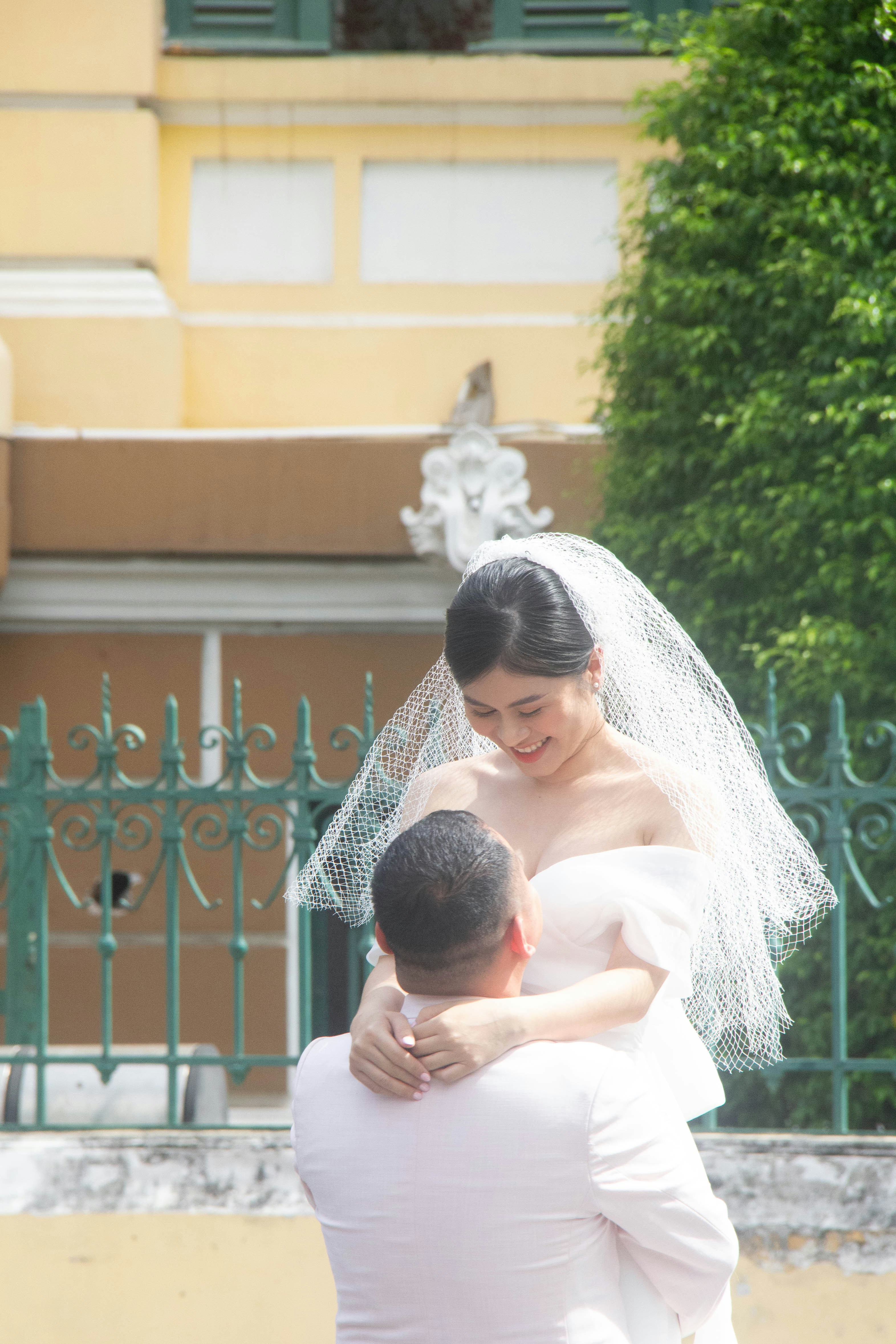 a woman in a wedding dress hugging a man