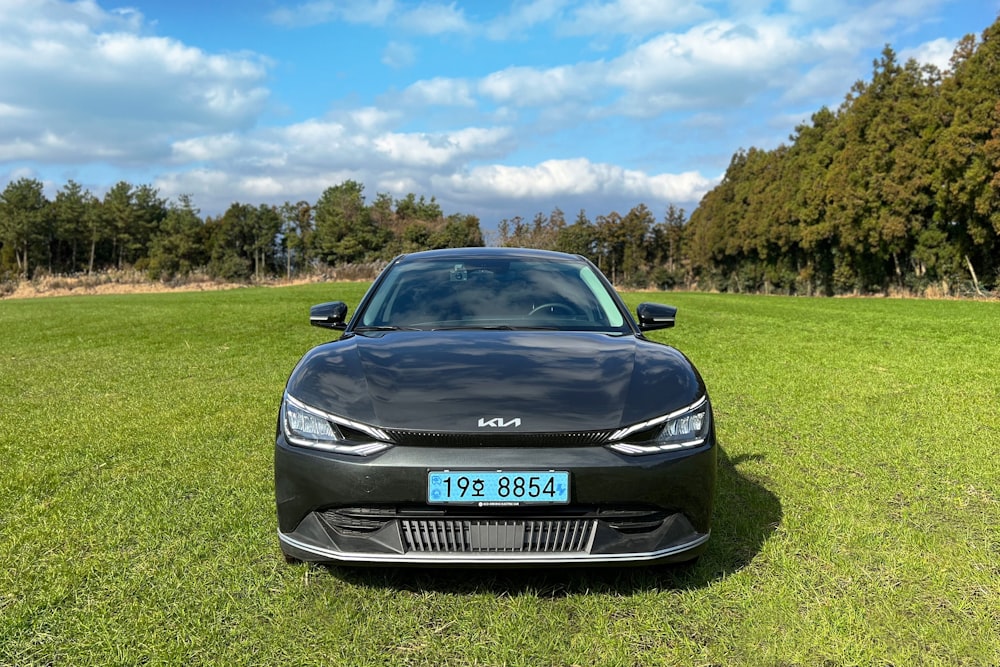 a black car is parked in the grass