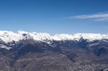 A panoramic view of mountain peaks under a clear blue sky, with winding trails visible below.
