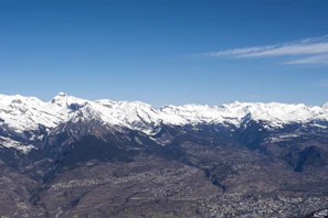 A panoramic view of mountain peaks under a clear blue sky, with winding trails visible below.