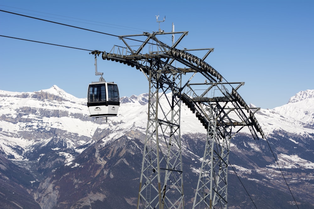 a cable car going up a mountain with snow covered mountains in the background