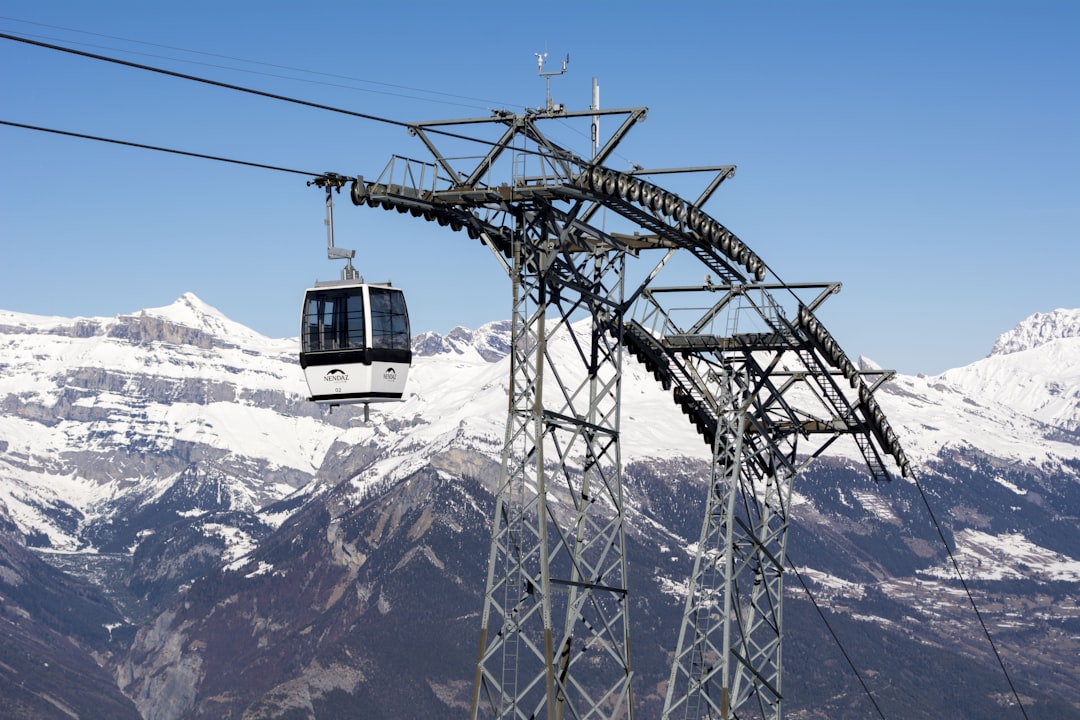 a cable car going up a mountain with snow covered mountains in the background,