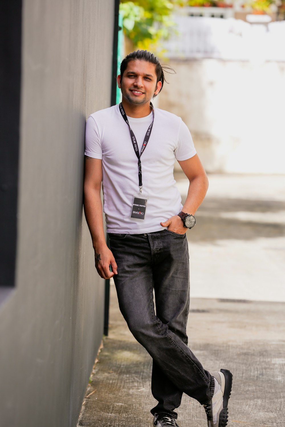 a man leaning against a wall with his hands on his hips