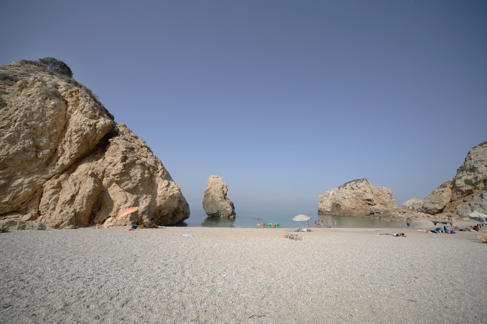 a sandy beach with a rock formation in the background