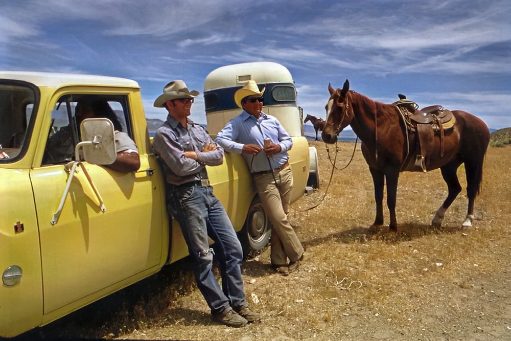 a couple of men standing next to a yellow truck