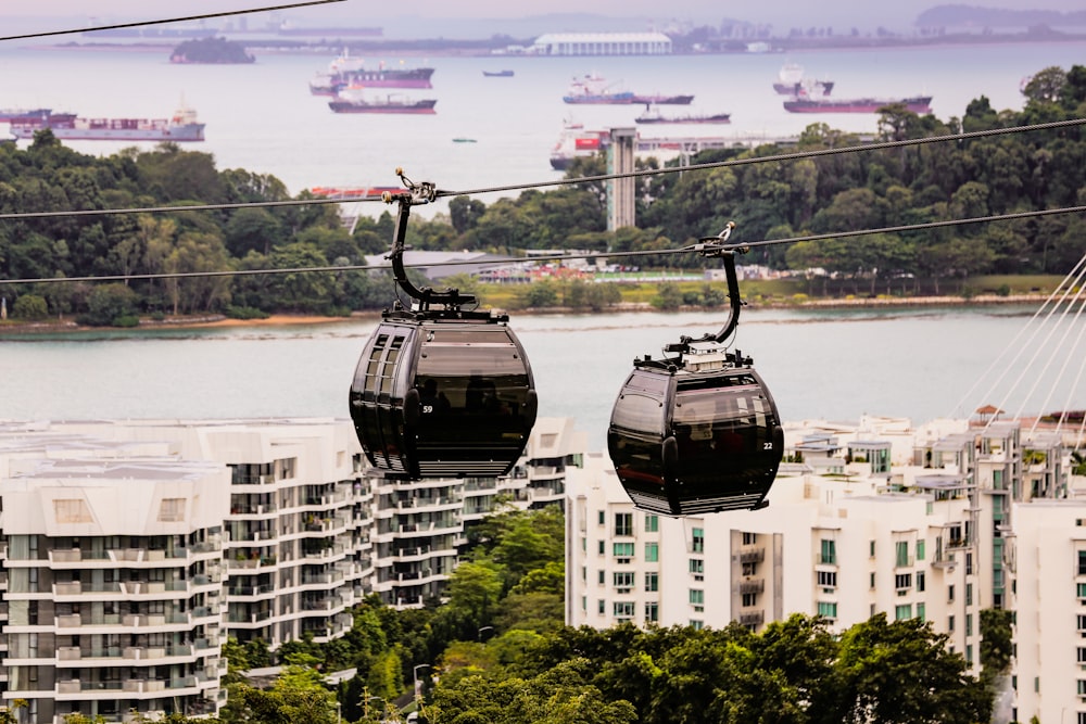 two gondola cars on a cable above a city