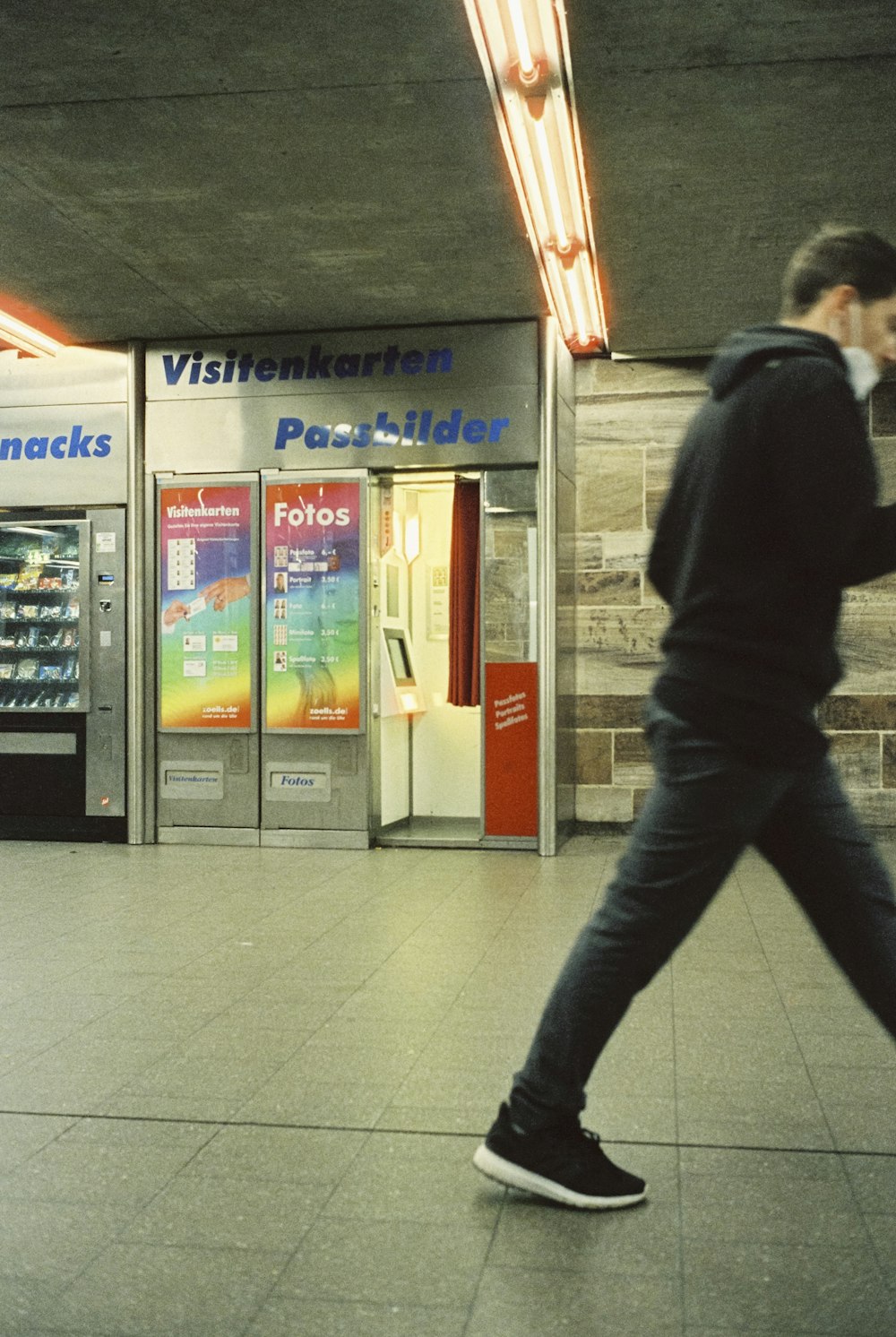 um homem está andando na frente de uma máquina de venda automática