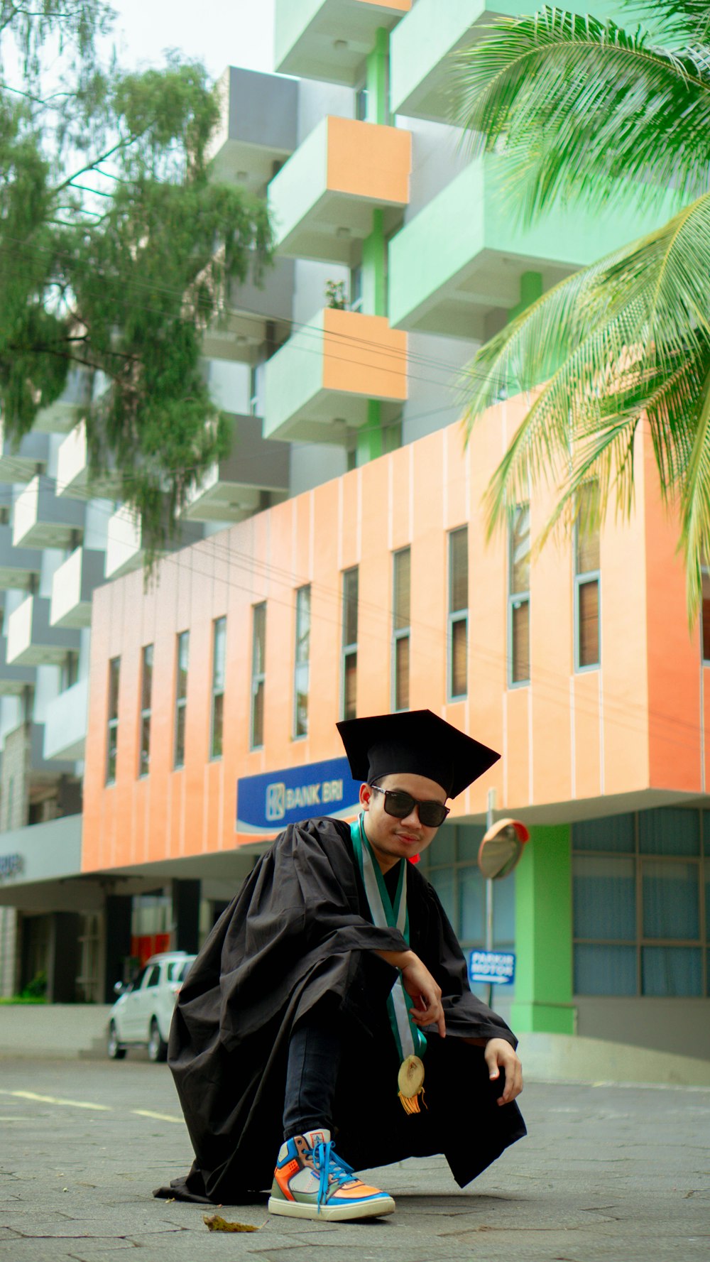 Un hombre sentado en el suelo con un vestido de graduación