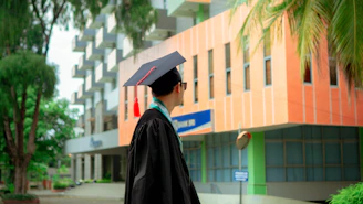a man in a graduation cap and gown standing in front of a building