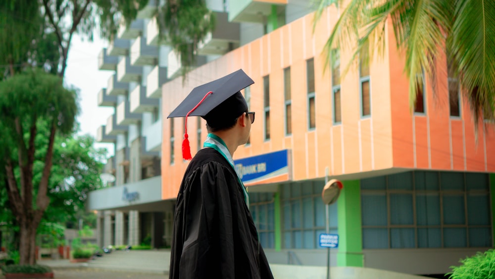 a man in a graduation cap and gown standing in front of a building