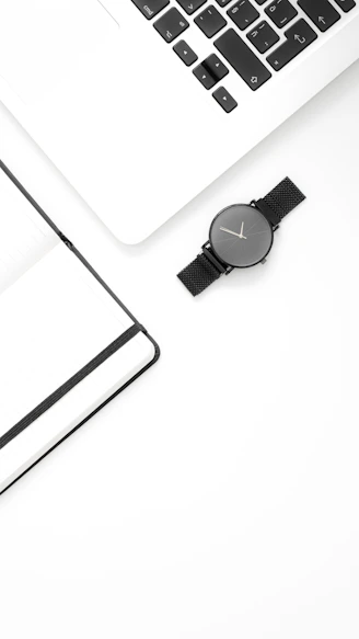 a white desk with a laptop and a watch