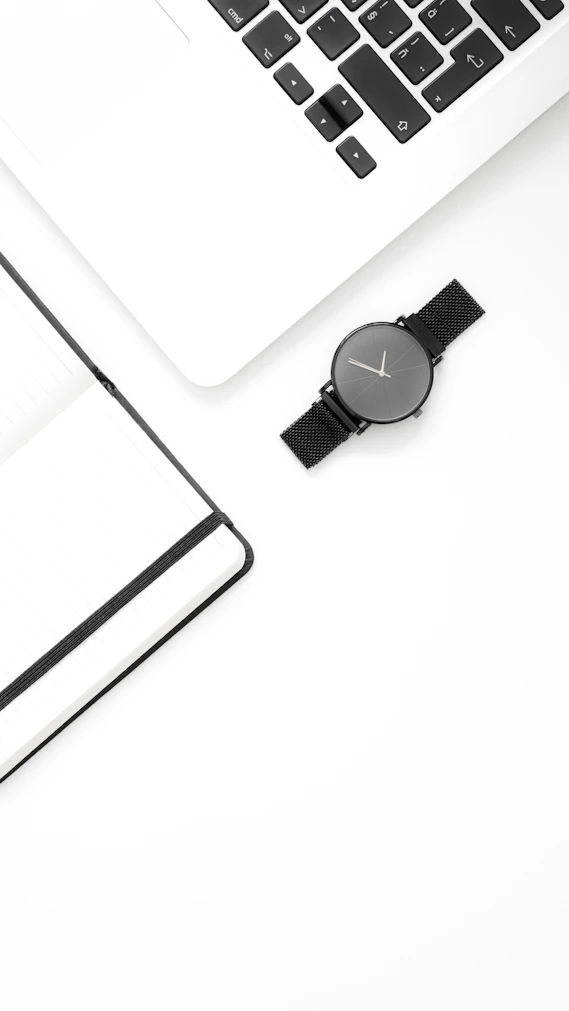 a white desk with a laptop and a watch