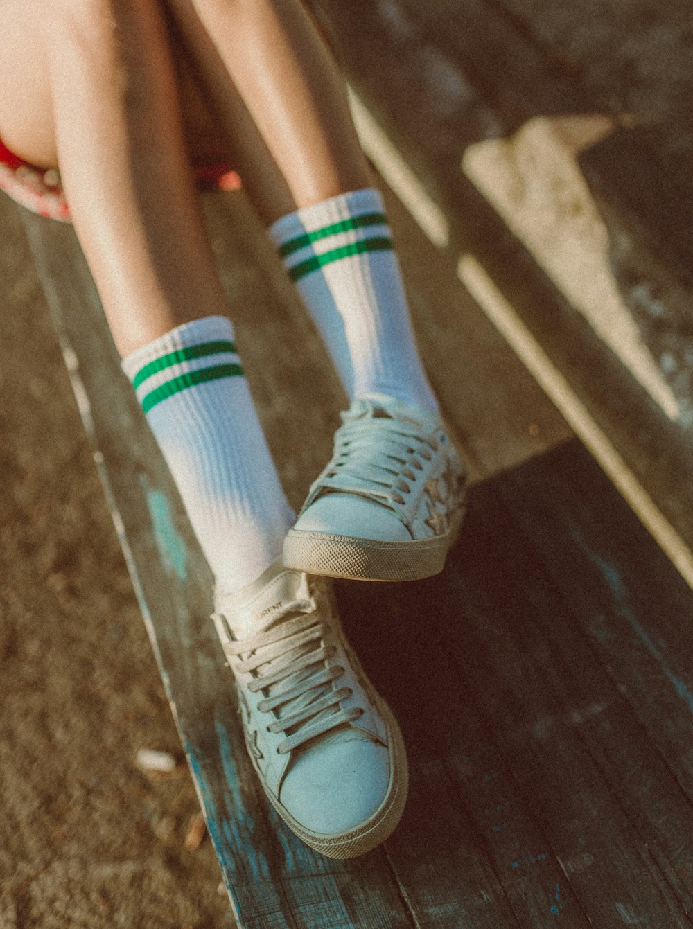 a person sitting on a bench wearing tennis shoes