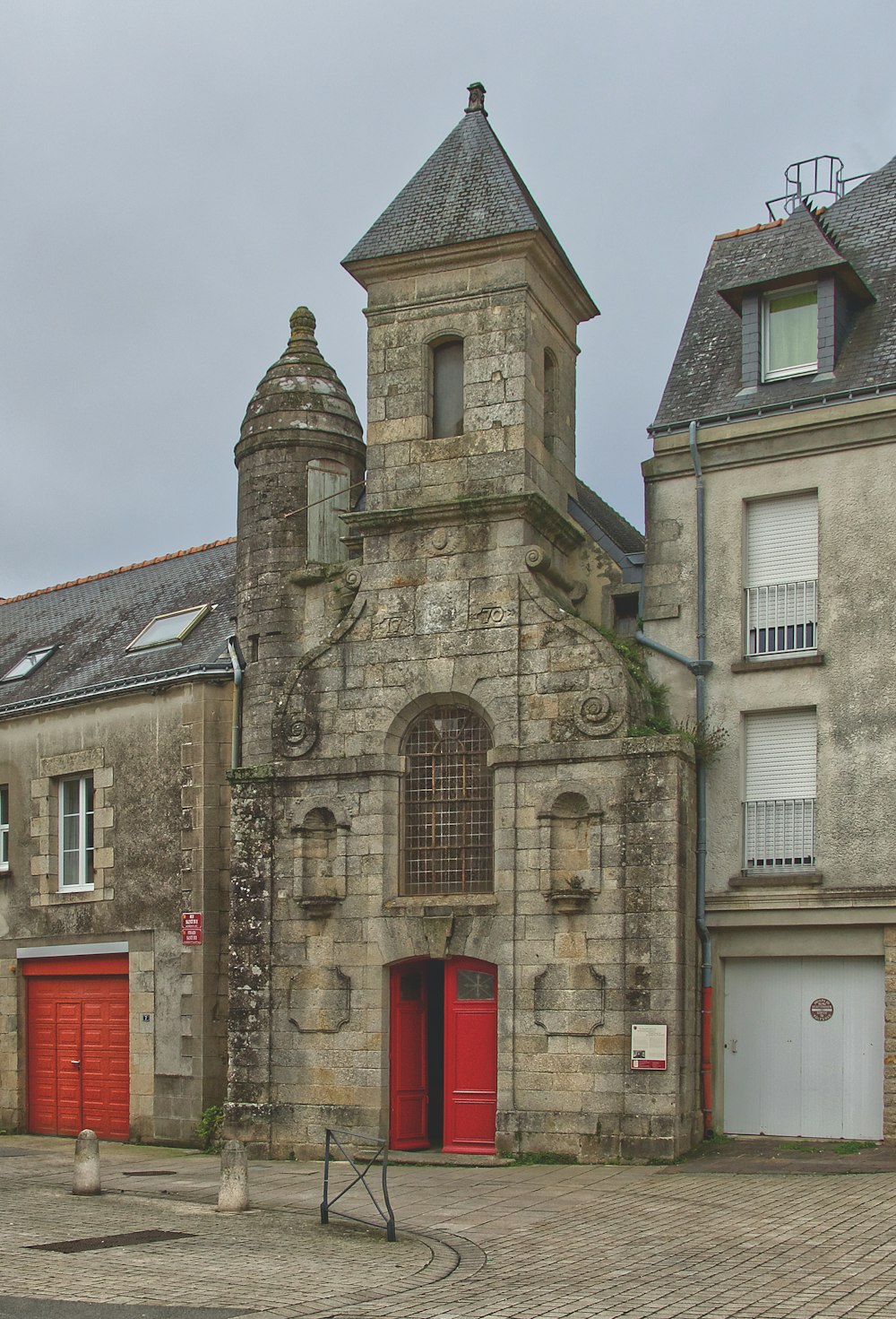 a stone building with a red door and a clock tower