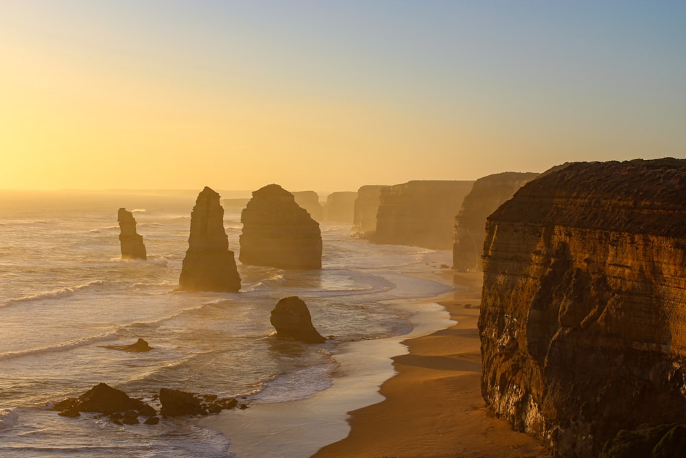 the sun is setting over the ocean and cliffs