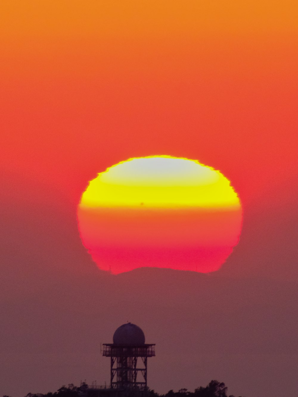 the sun is setting behind a tower in the sky