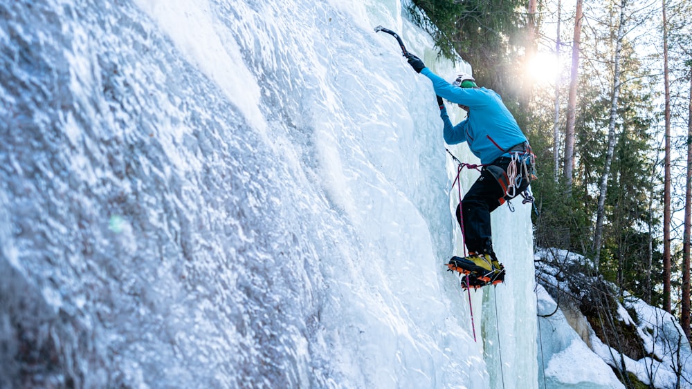 a man climbing up the side of a snow covered mountain