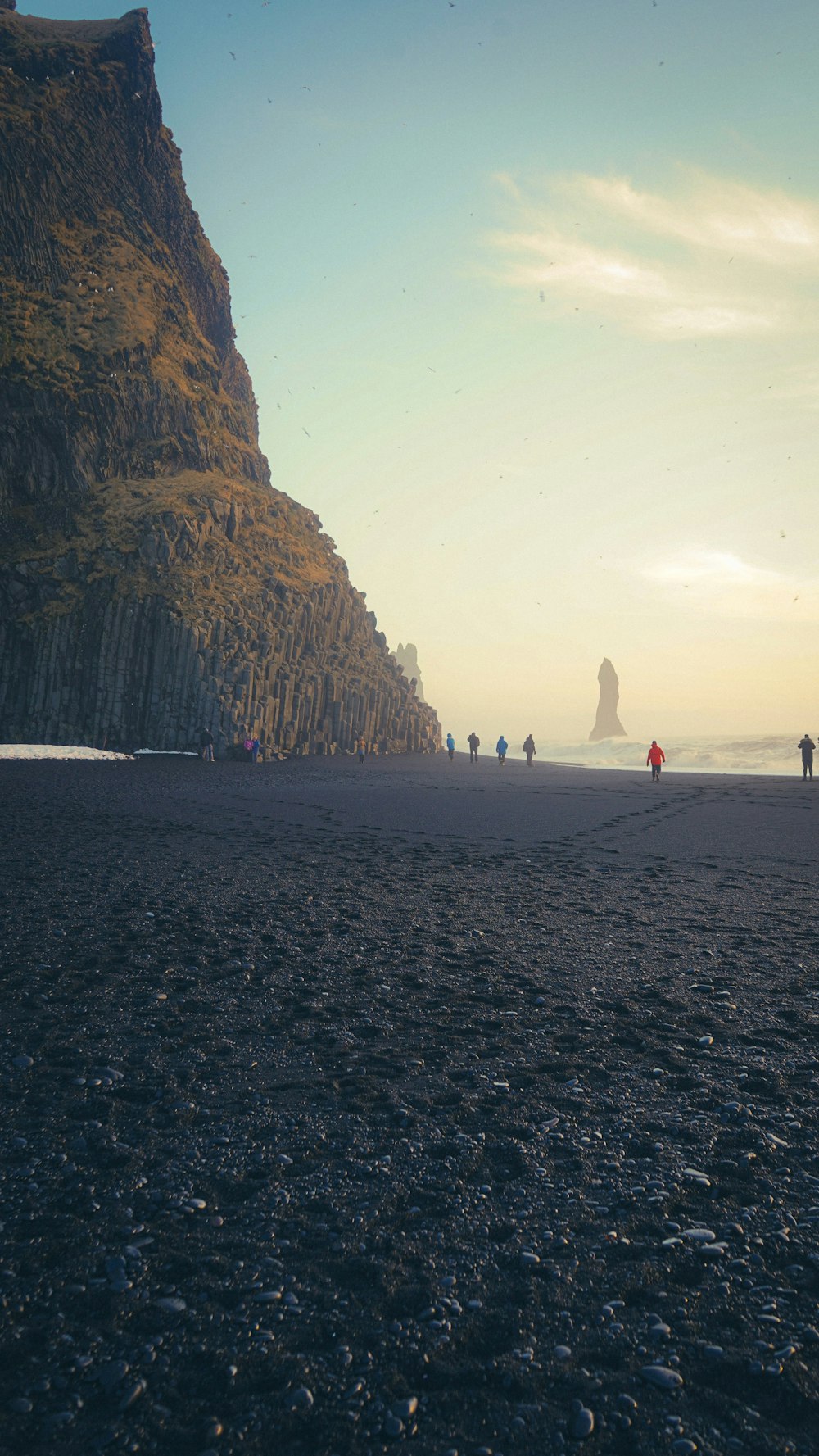 a group of people standing on top of a sandy beach