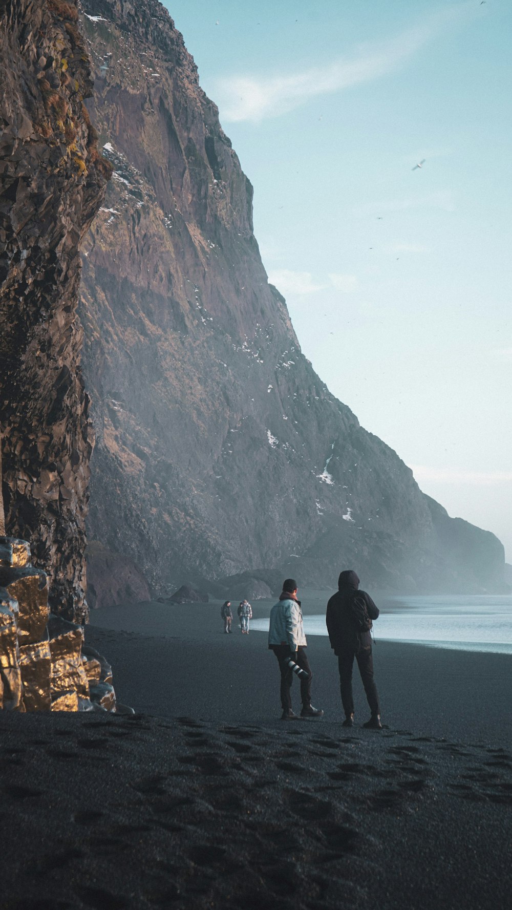 a couple of people standing on top of a beach