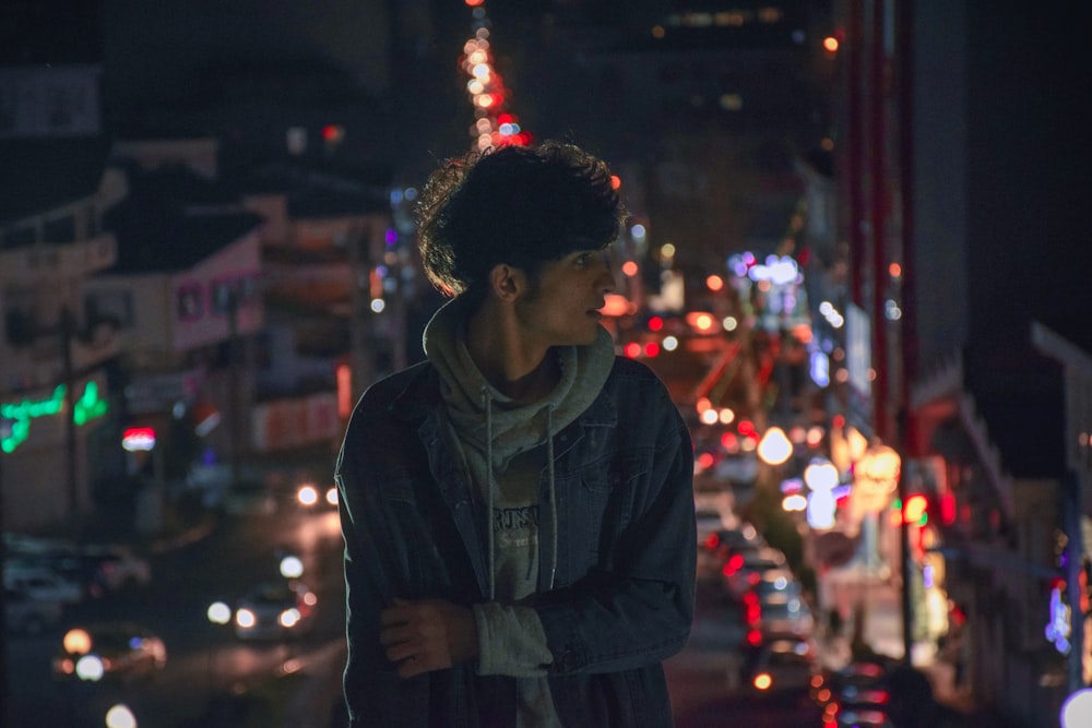 a young man standing in the middle of a city at night