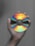 A hand holding a compact disc, which displays a spectrum of colors ranging from bright red, through orange, yellow, green, and blue, against a gray background.
