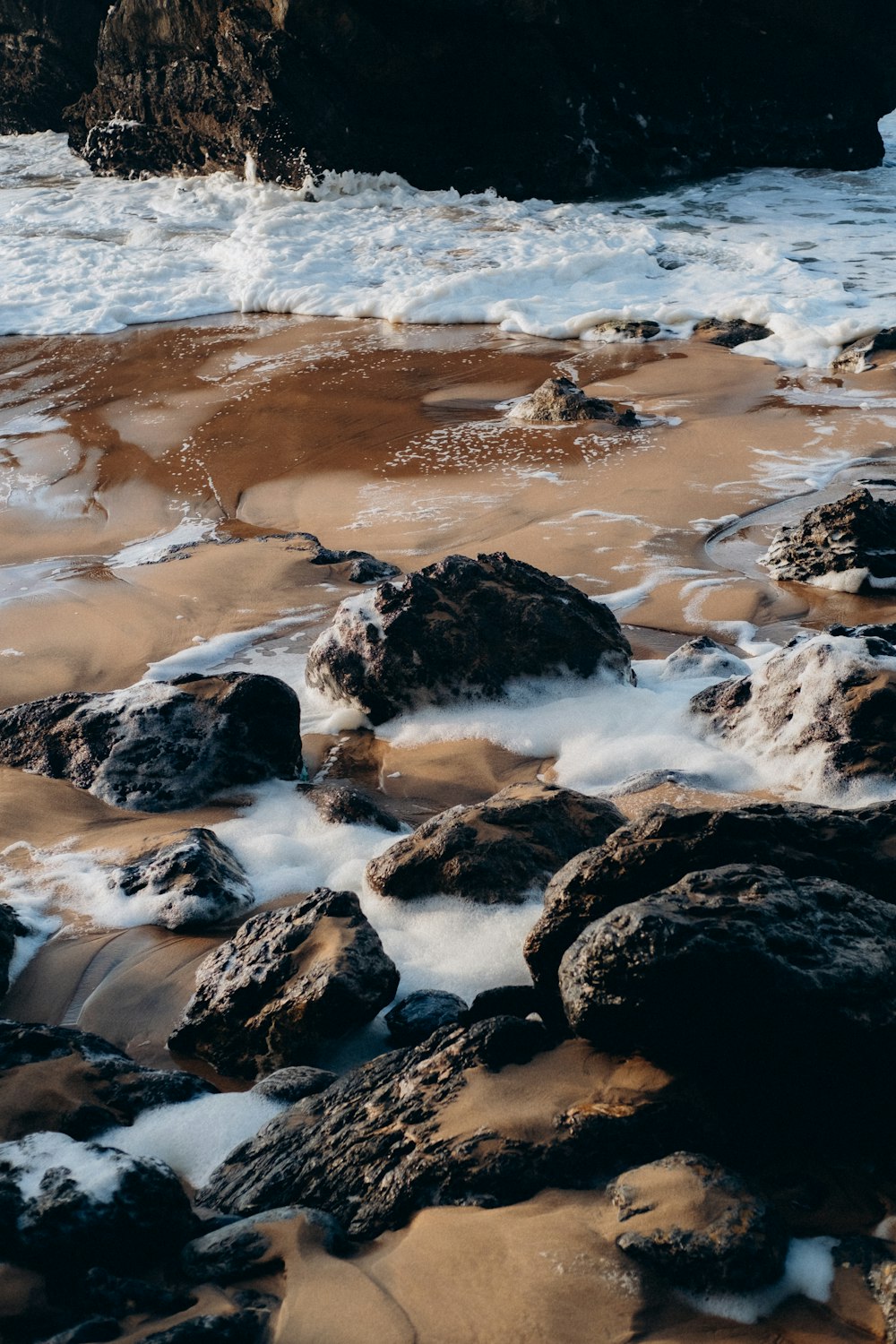 거품이 많은 물로 덮인 바위 해변