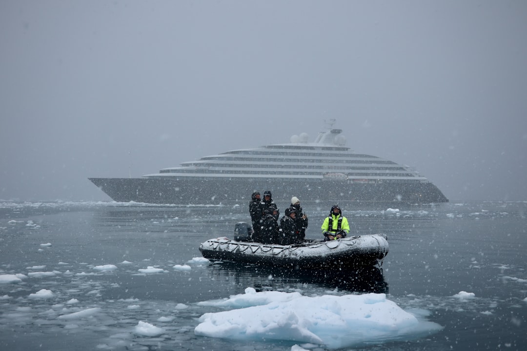 a group of people on a raft in the water, Ship and zodiac boat in Antarctic blizzard