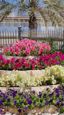 A tiered freestanding garden planter tower filled with vibrant flowers against a sunny backyard.