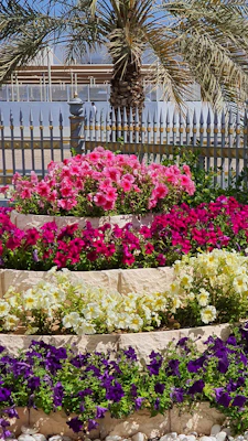 A tiered freestanding garden planter tower filled with vibrant flowers on a sunny patio