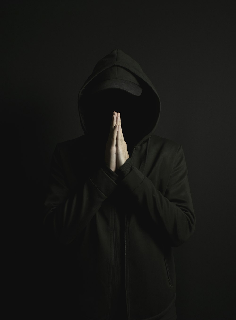 a man in a black hoodie is covering his face with his hands