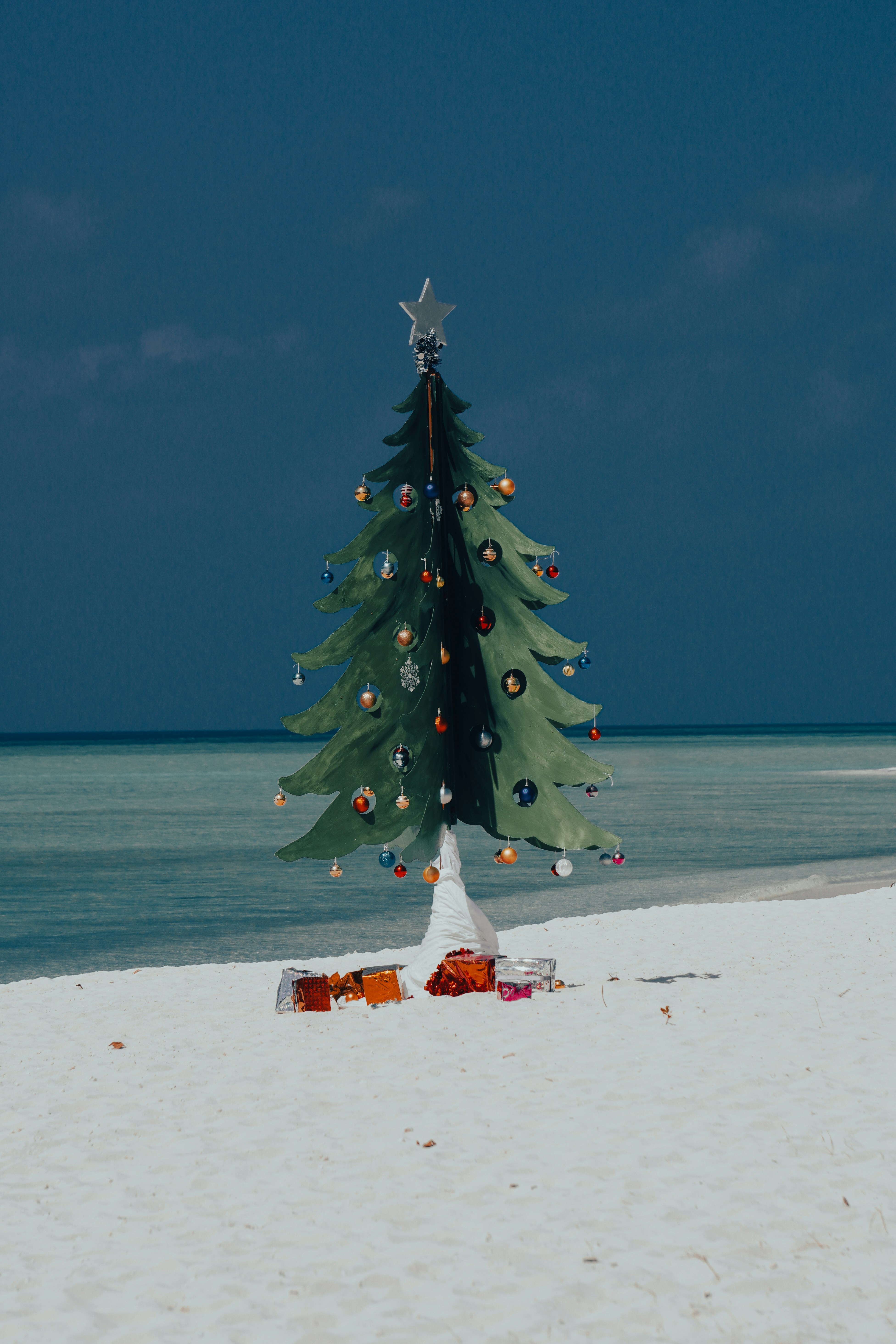 a christmas tree on the beach with a star on top