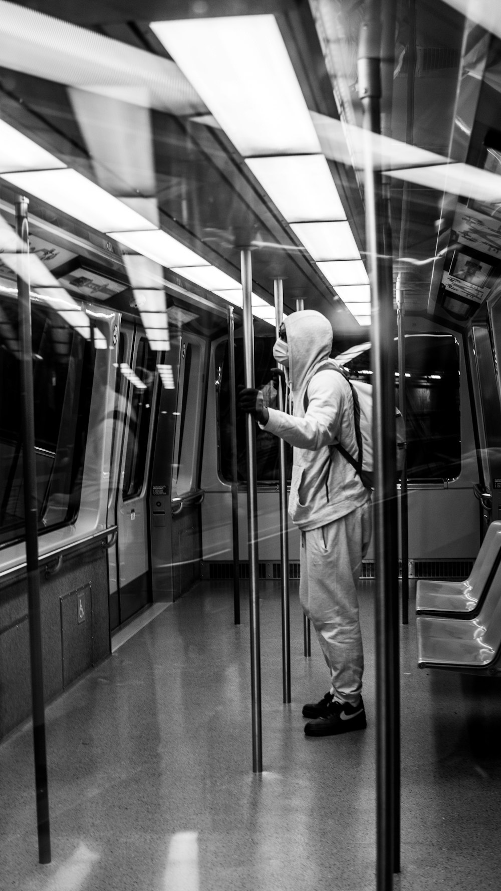 a man in a hoodie standing on a subway train