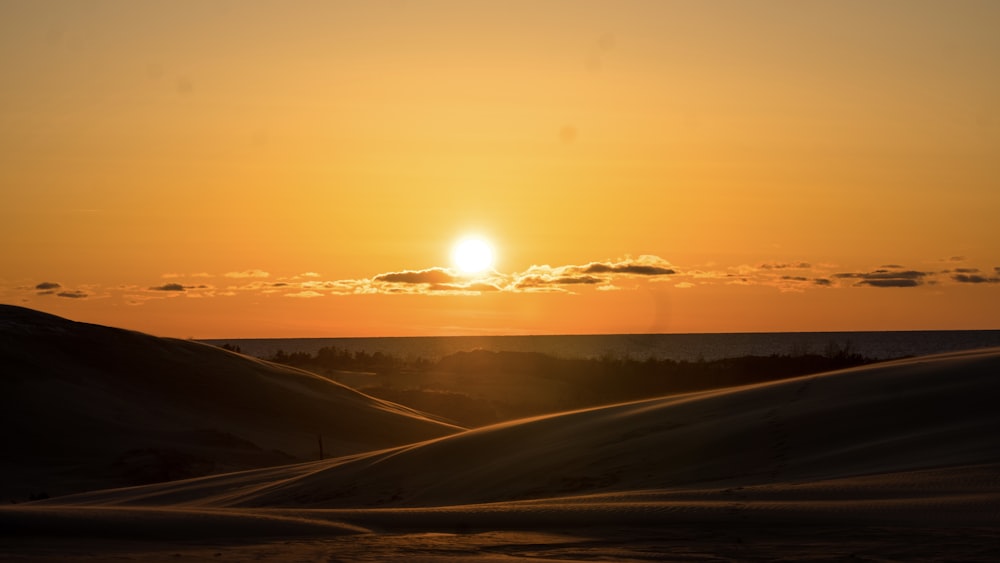 the sun is setting over the sand dunes