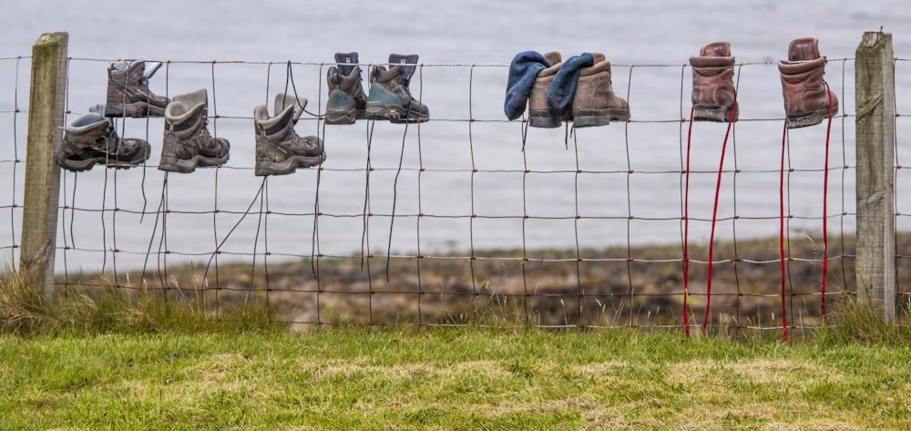a wire fence with several pairs of shoes hanging on it