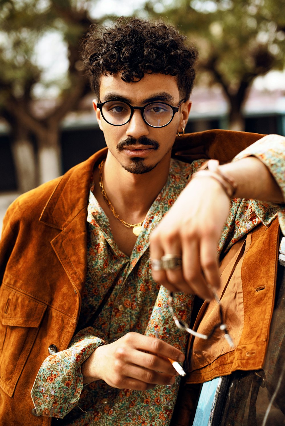 a man with glasses holding a cigarette in his hand