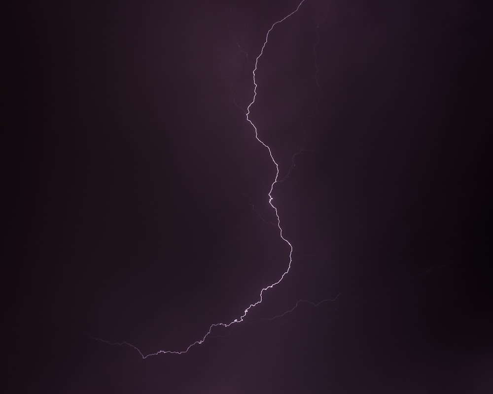 a lightning bolt is seen in the dark sky