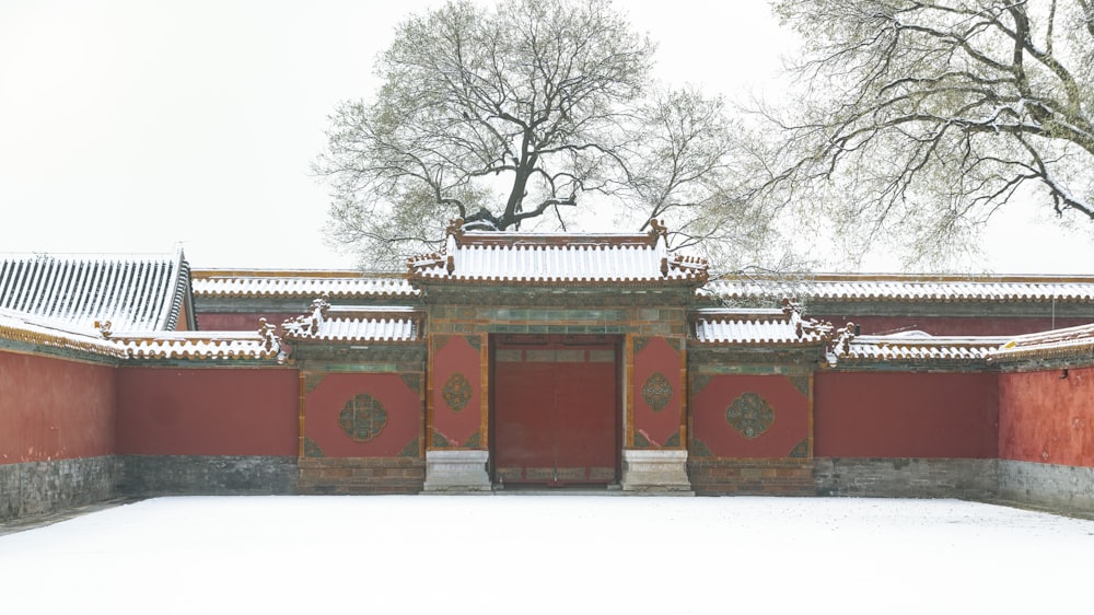 a red building with a white roof covered in snow
