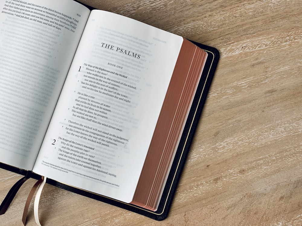 an open book on a wooden table with a ribbon