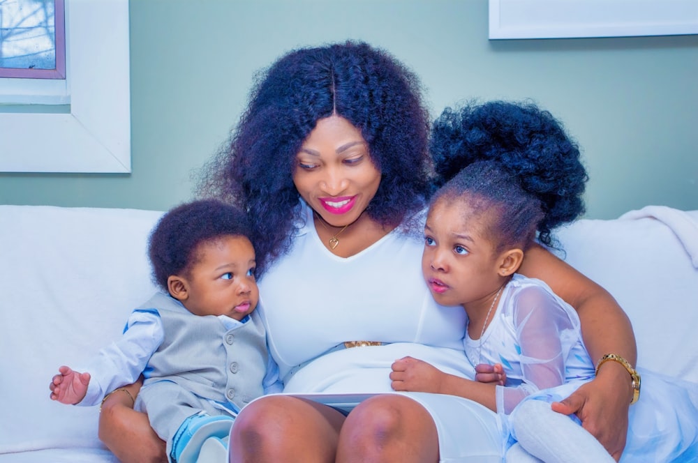 a woman sitting on a couch with two children