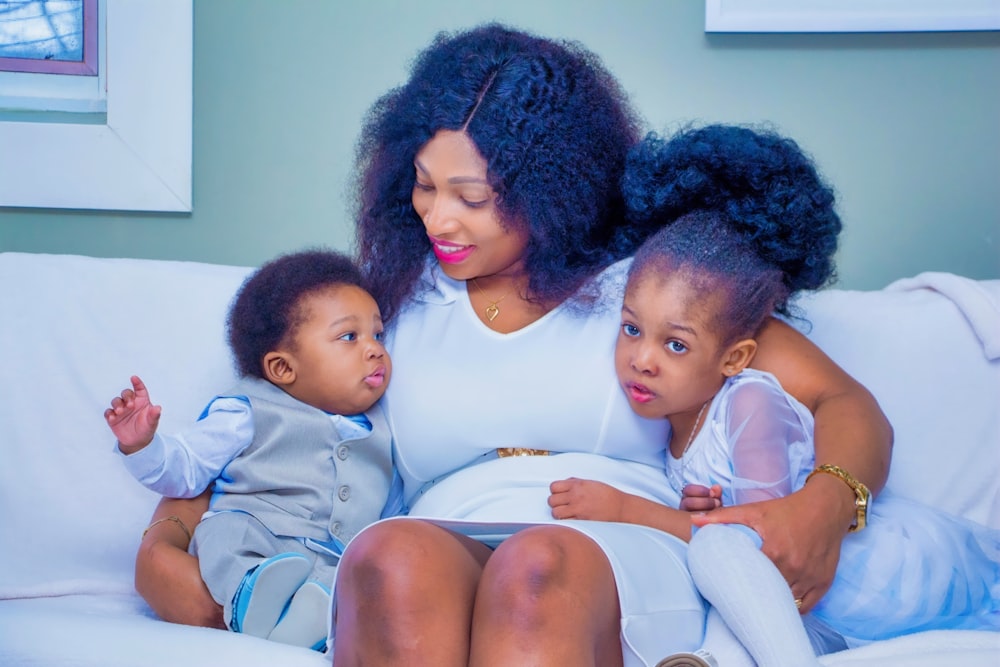 a woman and two children sitting on a couch