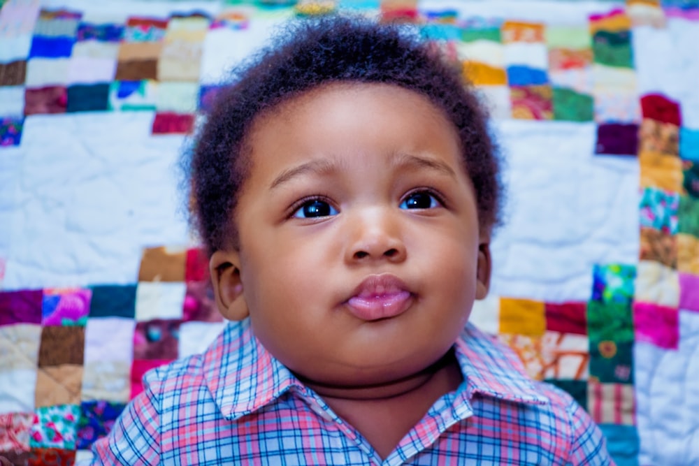 a small child with a patchwork shirt on