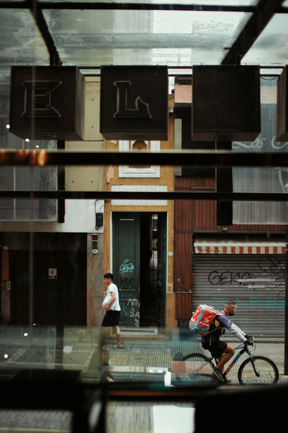 a man riding a bike down a street next to a tall building