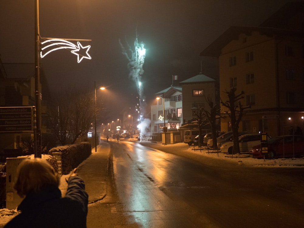 a person taking a picture of fireworks on a street