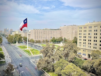 a flag flying in the air over a city street