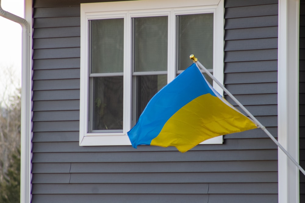 a blue and yellow flag hanging from the side of a house